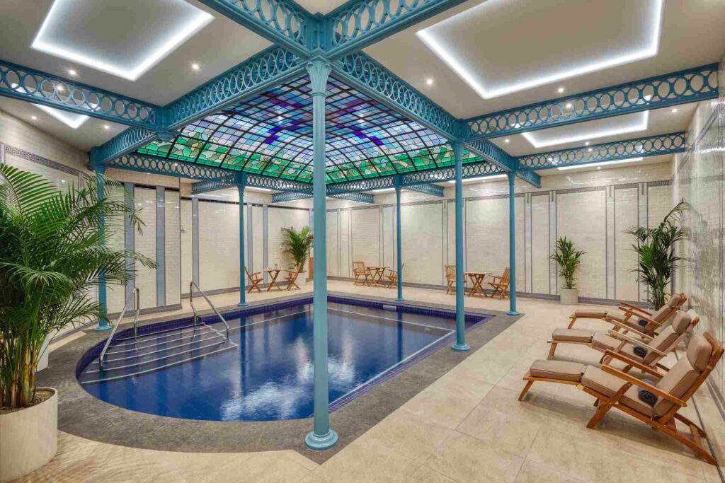  Indoor spa pool at Buxton Crescent Hotel, featuring a glass canopy supported by ornate turquoise ironwork