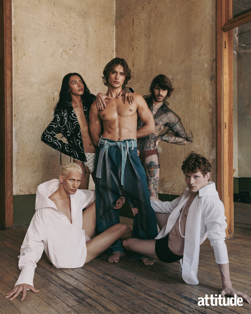 One model topless in denim stands and four other models lean against him in exposing shirts and underwear