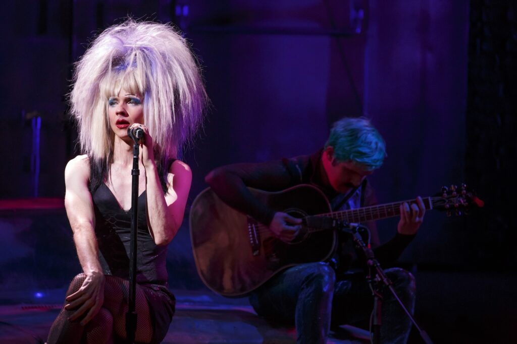 John on stage as Hedwig in a blonde wig