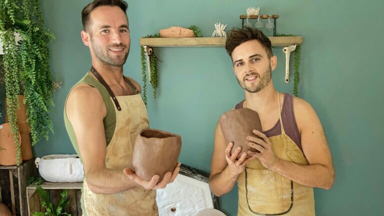 Adam Johnson and Dan Mackey stood in front of their kiln both holding clay pots