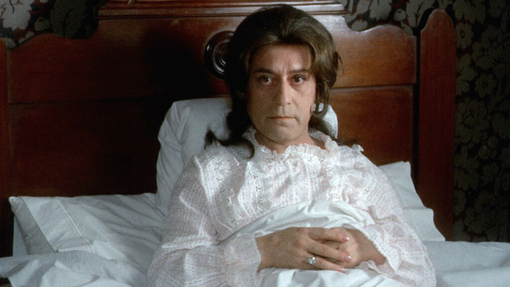 a person with long hair lying in a bed in a nightgown