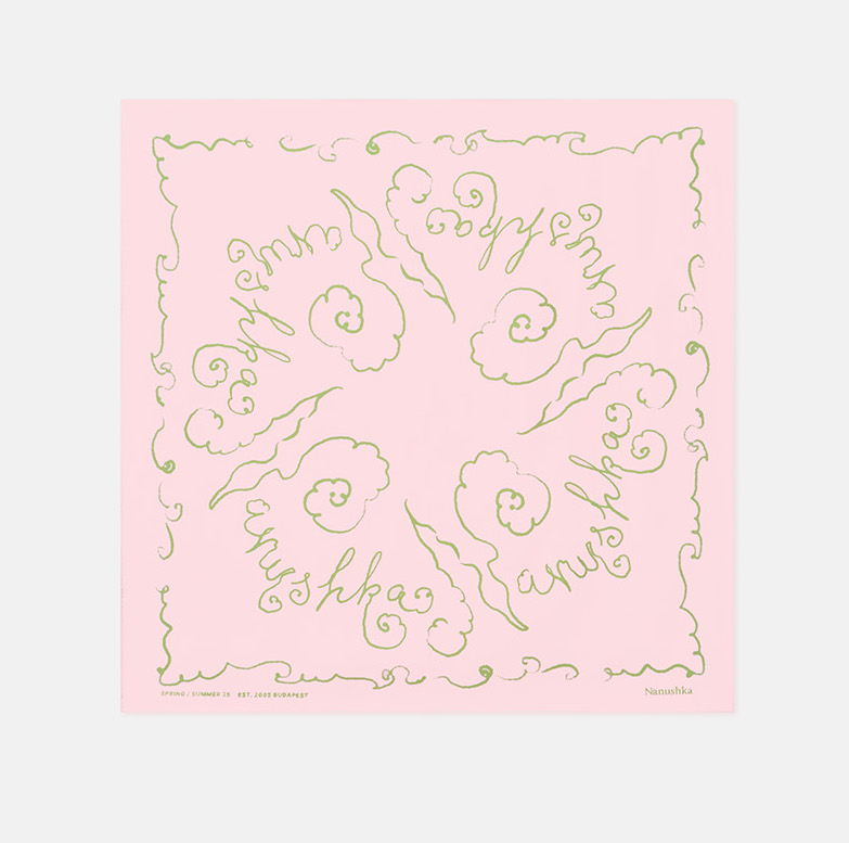 Square pink scarf with green decorative script and swirl designs, featuring the brand name "Nanushka" in a repeating pattern.