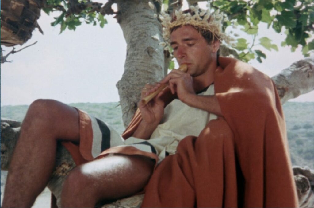 a man in roman robes sitting against a tree