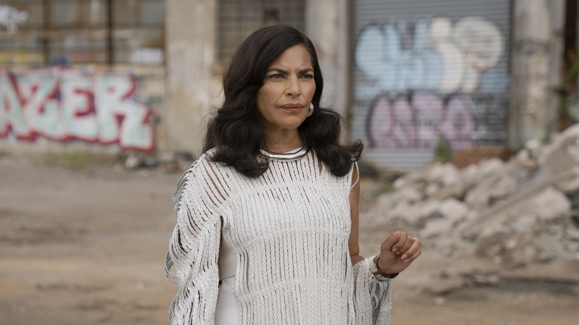 Sarita Choudhury as Seema in And Just Like That... (Image: Sky/Now) in a white dress with a crumbling building in the background