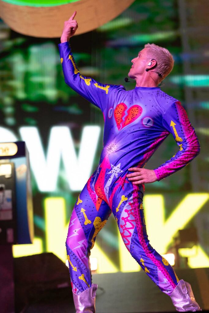 Jake Shears performing in a colourful, tight-fitting bodysuit with a heart design