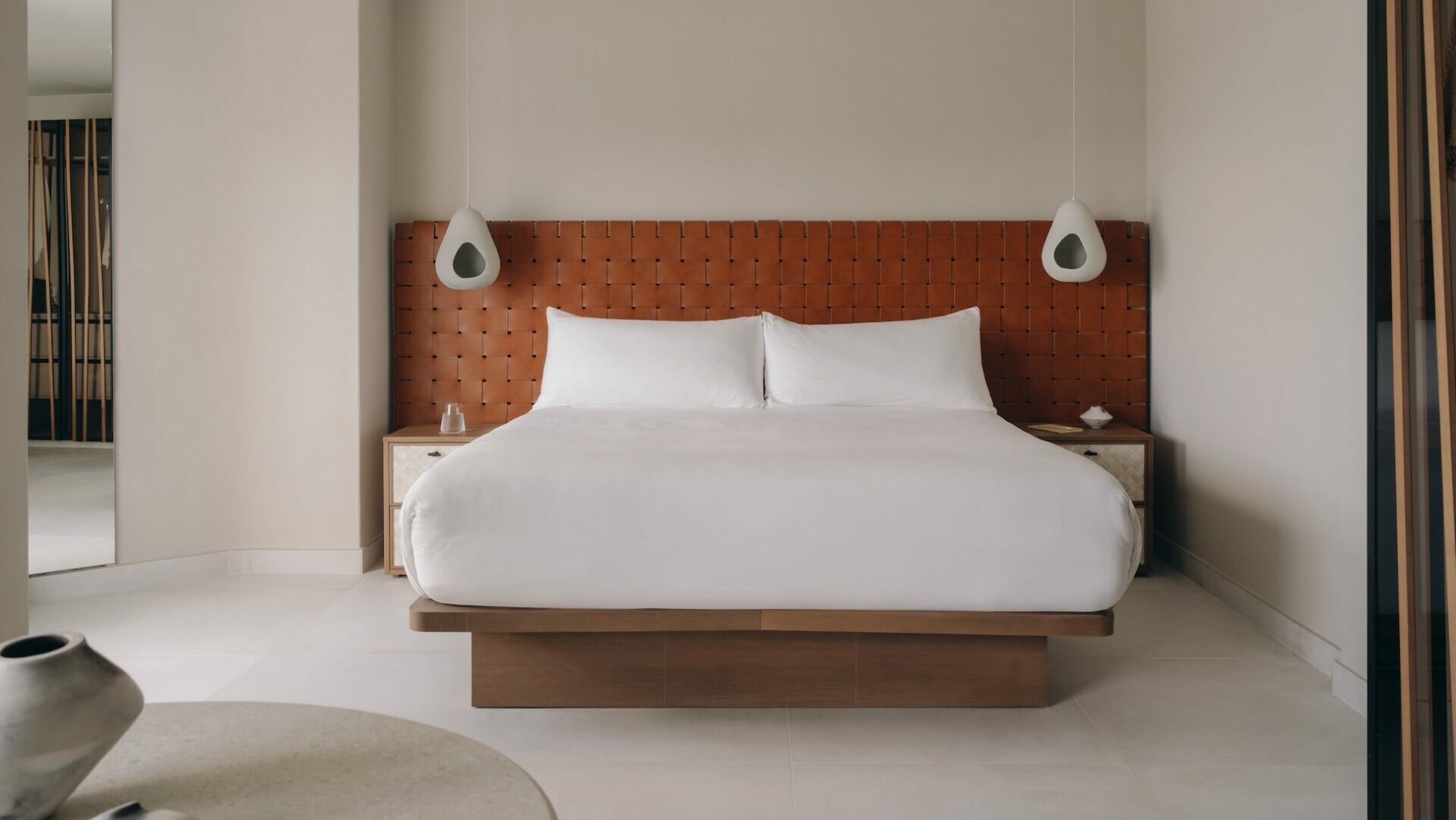 pic of bedroom with white bed sheets and cream floor and walls