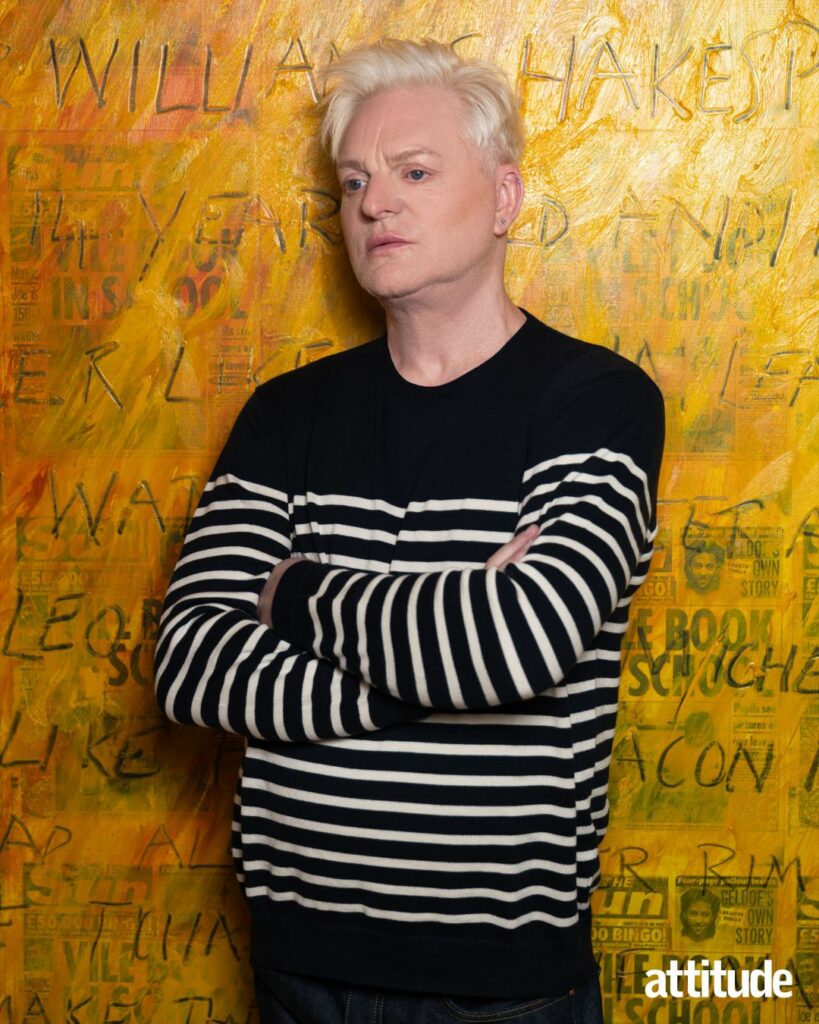 Andy Bell wearing a black and white striped top against a yellow backdrop