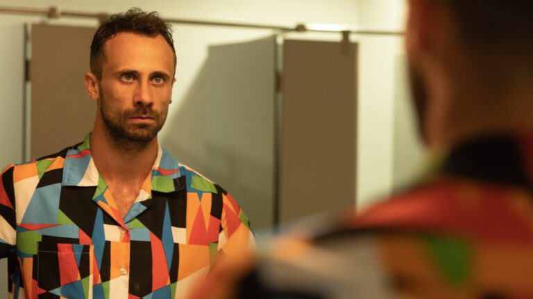 Oriol Pla in I, Addict, in a colourful shirt looking into a mirror