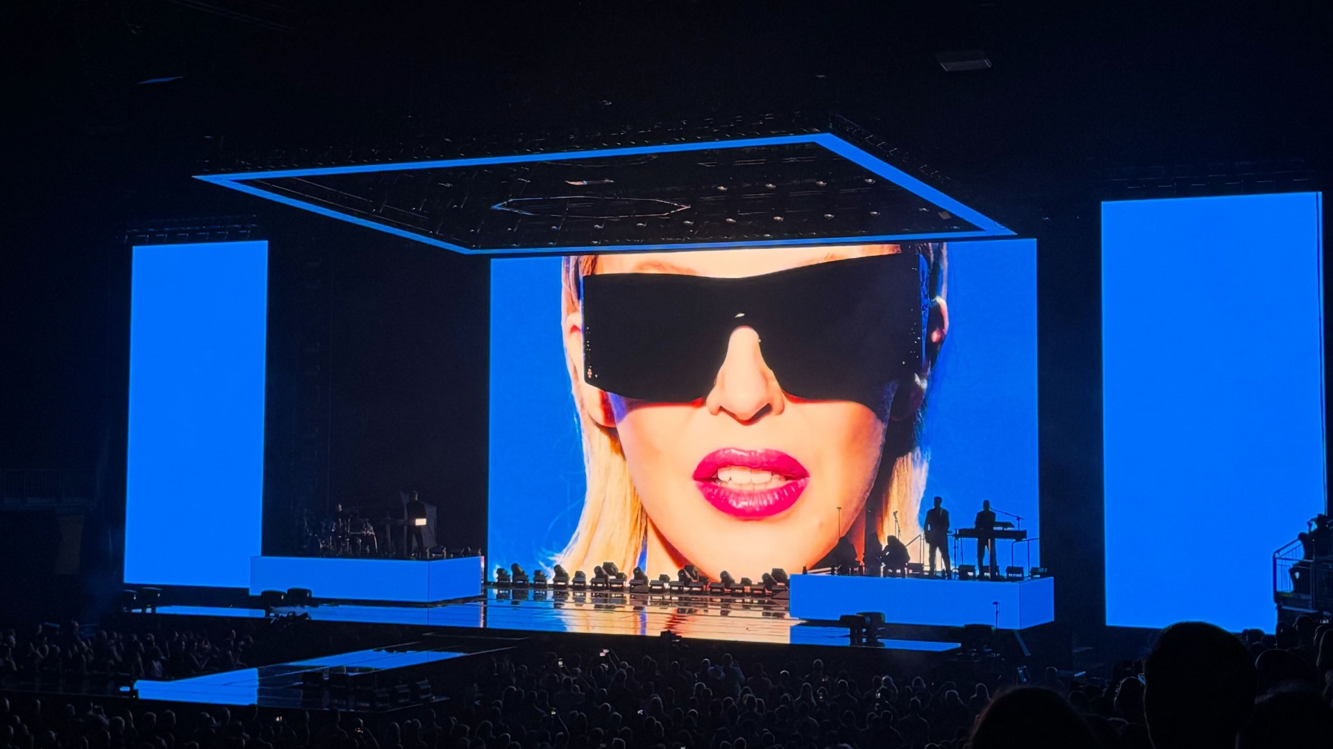 Kylie Minogue wearing sunglasses on a screen at the O2 London