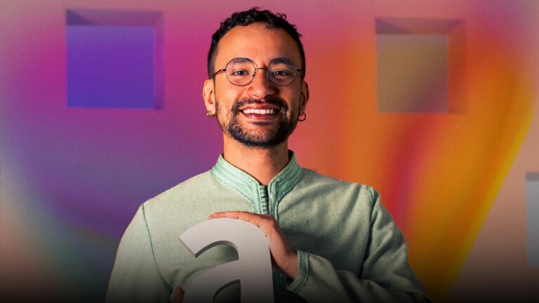 A smiling man holding an Attitude Pride Award against a colourful backdrop