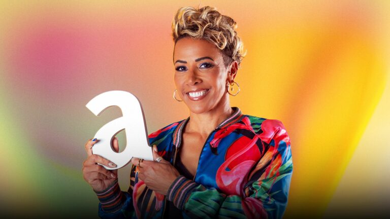 Kellly Holmes wearing a colourful bomber jacket holding an Attitude Pride Award