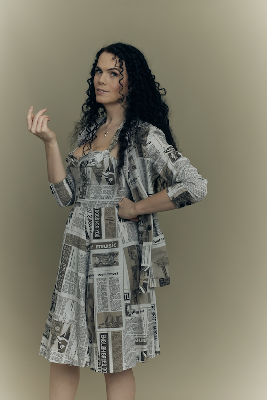 Jordan Gray in newsprint dress looking at camera - attitude photoshoot