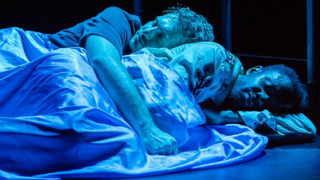Alexander Lincoln and Omari Douglas wrapped in a sheet going to sleep on stage at This Bitter Earth