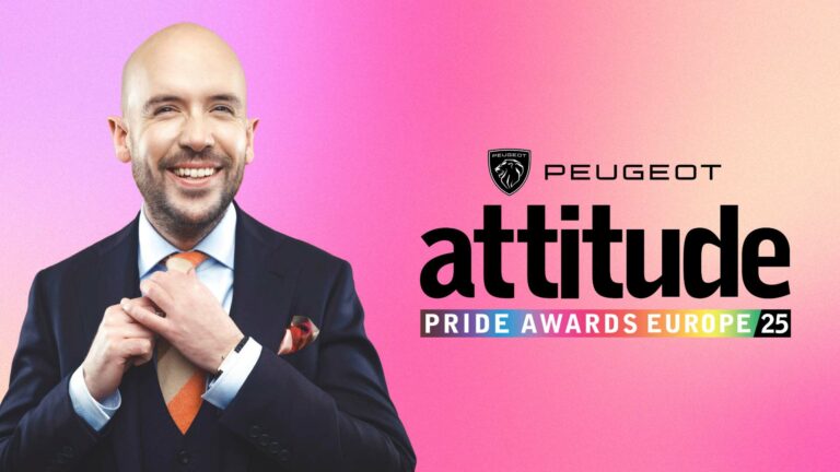 Tom Allen wearing a suit in smiling against a pink backdrop with the Peugeot Attitude Pride Awards Europe logo in the background