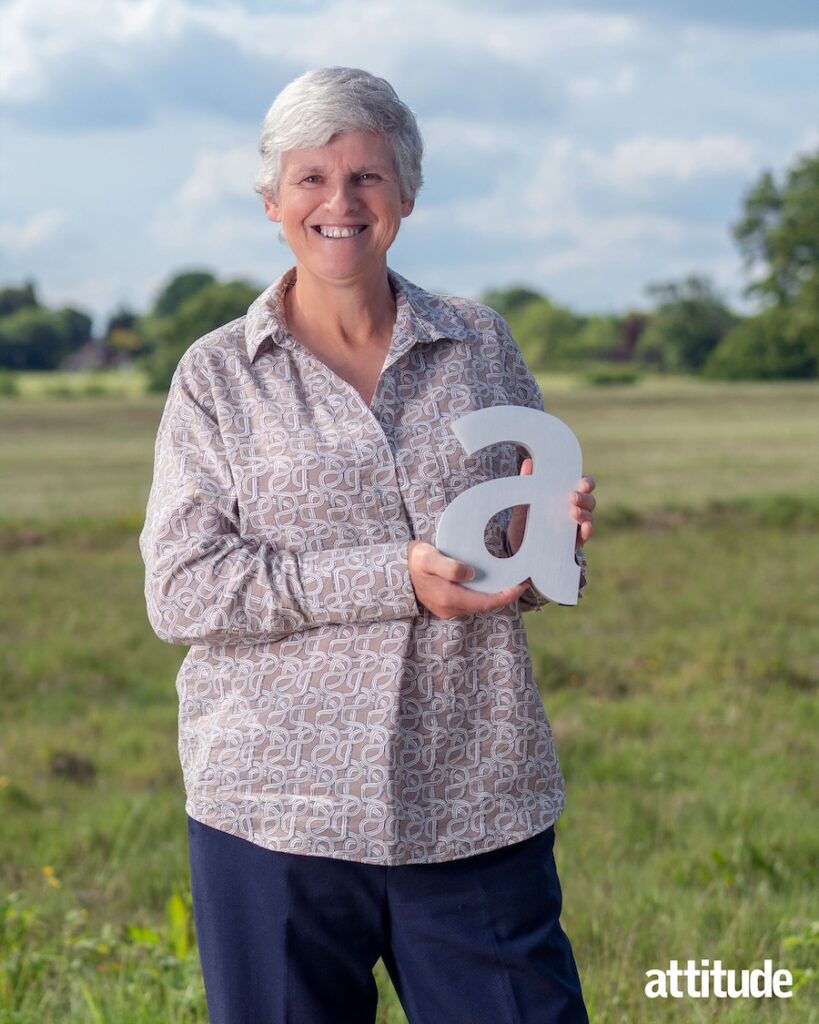 Tracey holding her award in a green field, wearing a light purple blowse