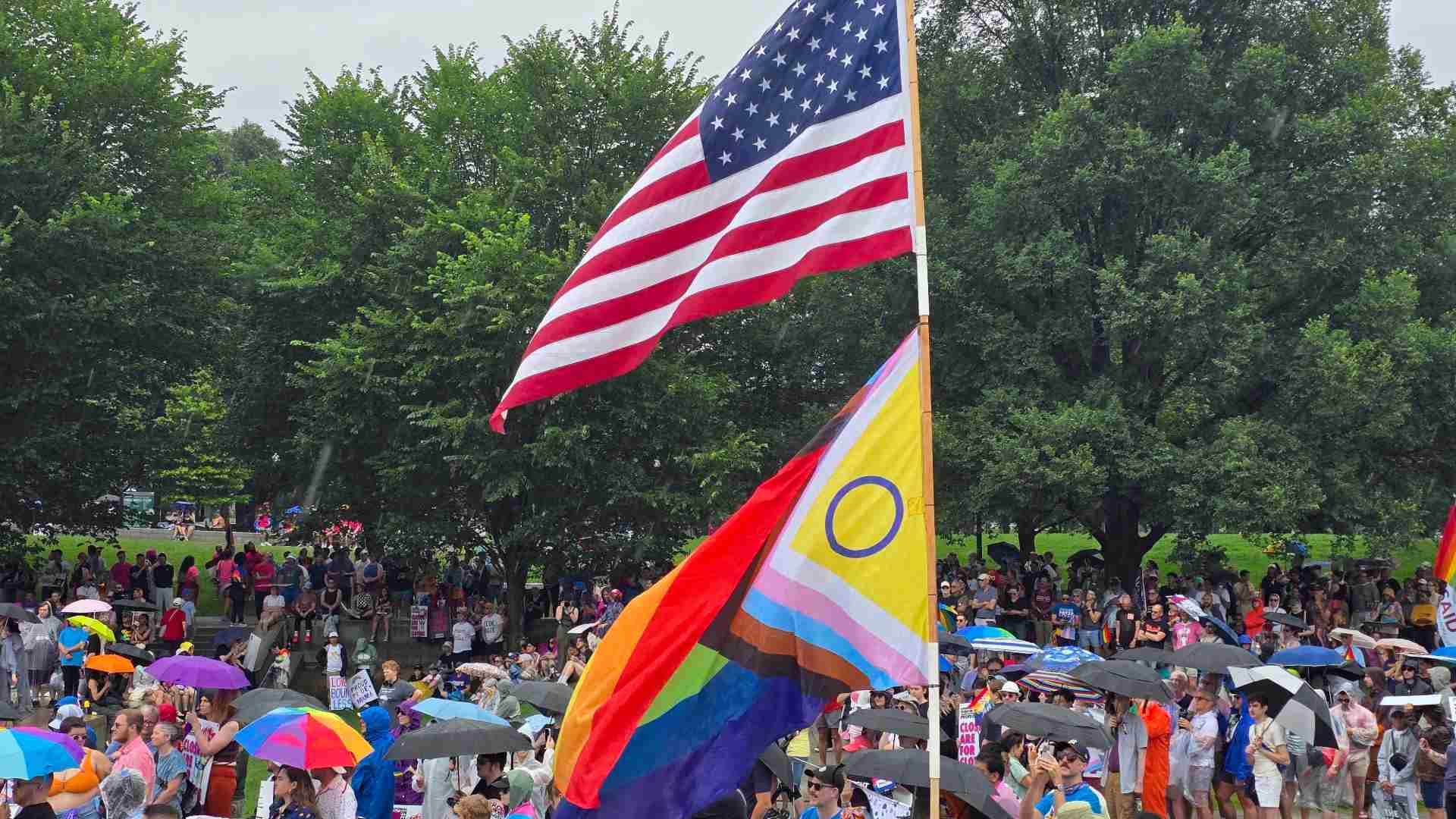 Crowd at a Pride event with US and LGBTQ+ flags flying in the foreground