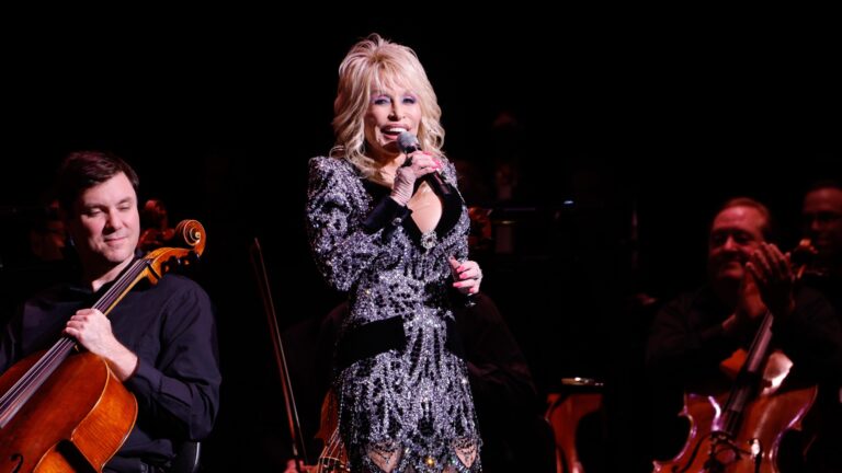 Dolly Parton standing on stage in a sequinned bodysuit