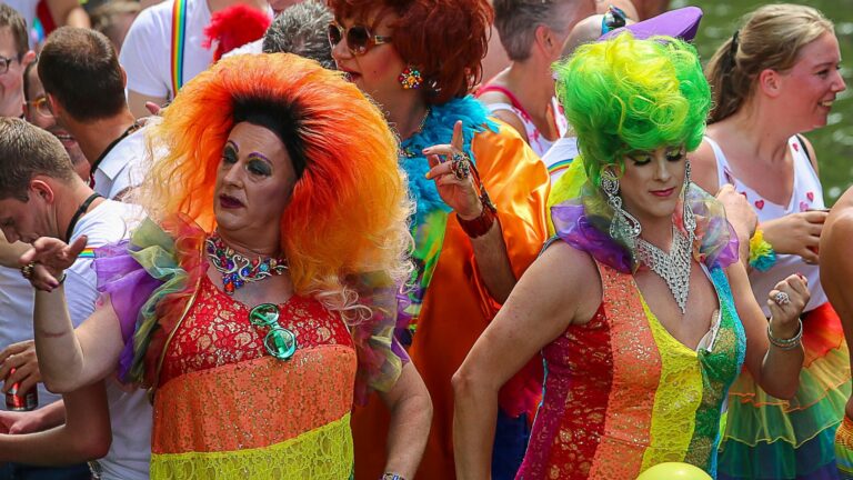 Two drag queens and other party-goers dancing at a Pride party