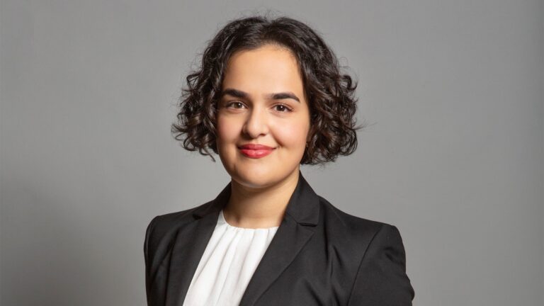 a head and shoulders shot of Nadia in white top and grey blazer with hair down