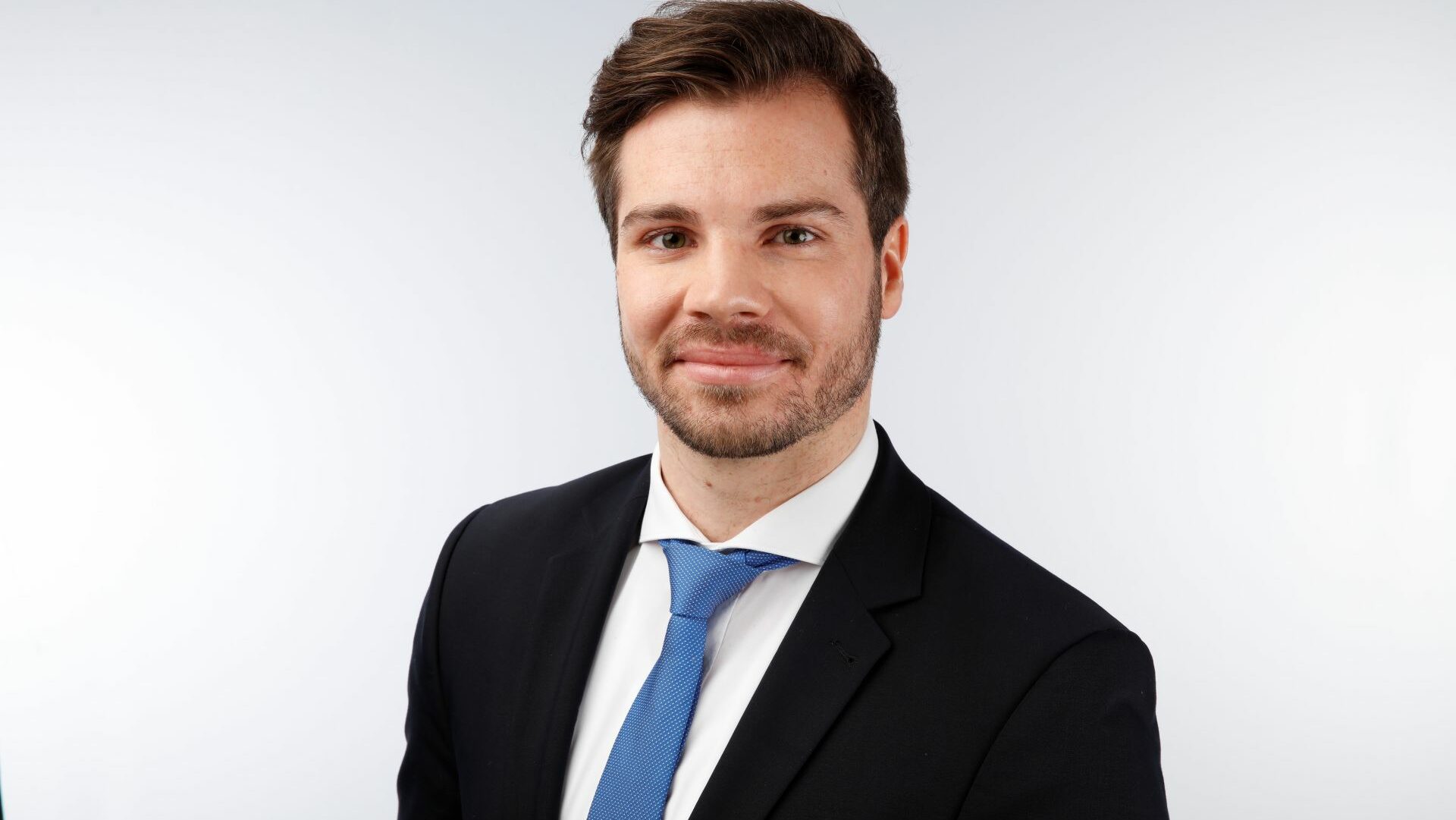 A portrait shot of a smiling man in a business suit