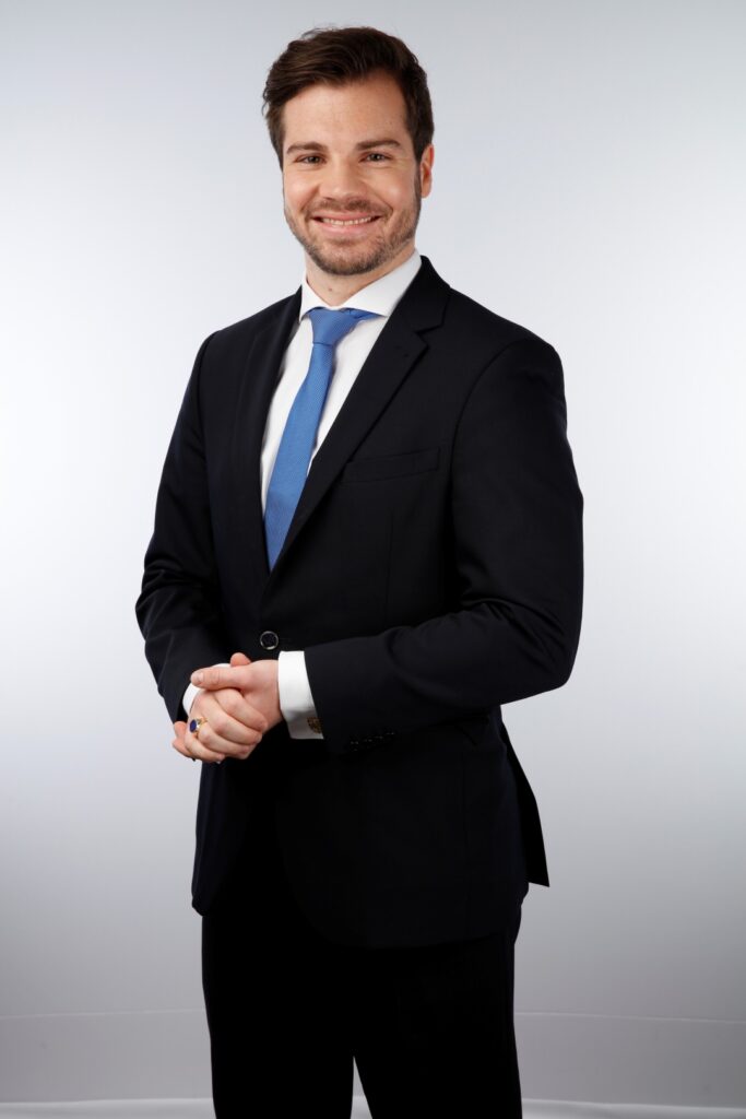 A portrait shot of a smiling man in a business suit