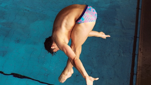 Man diving into a swimming pool in patterned swimwear