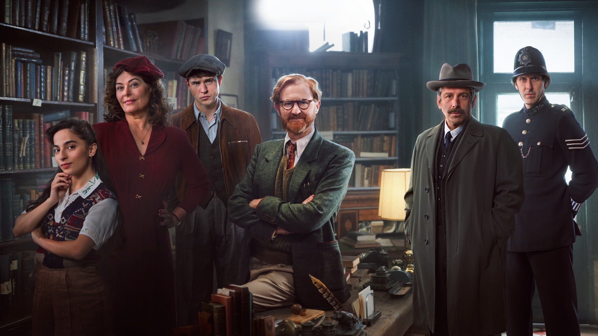 Promo still of the cast of bookish in period attire sitting in Book's bookshop