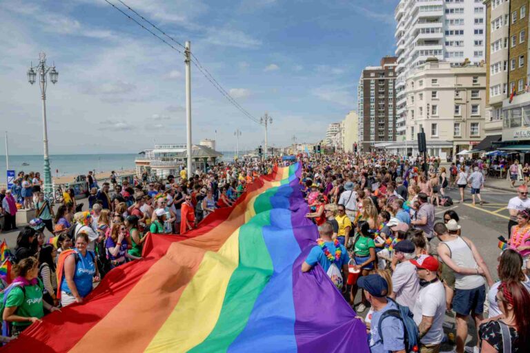 Crowds carrying a rainbow flag on the streets of Brighton