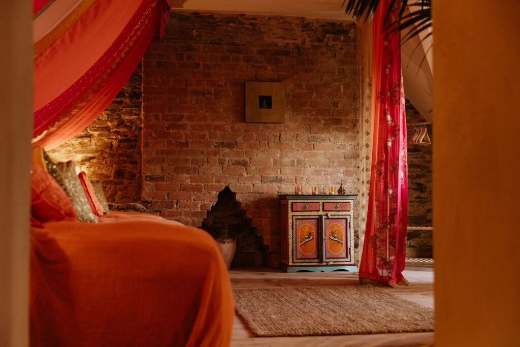 a room at the dreaming, with red curtains and orange bed spread