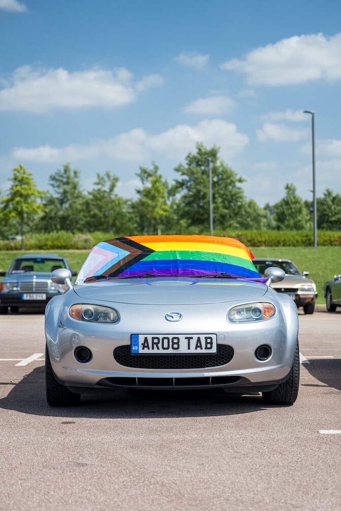A Mazda with a pride flag laid on the windscreen