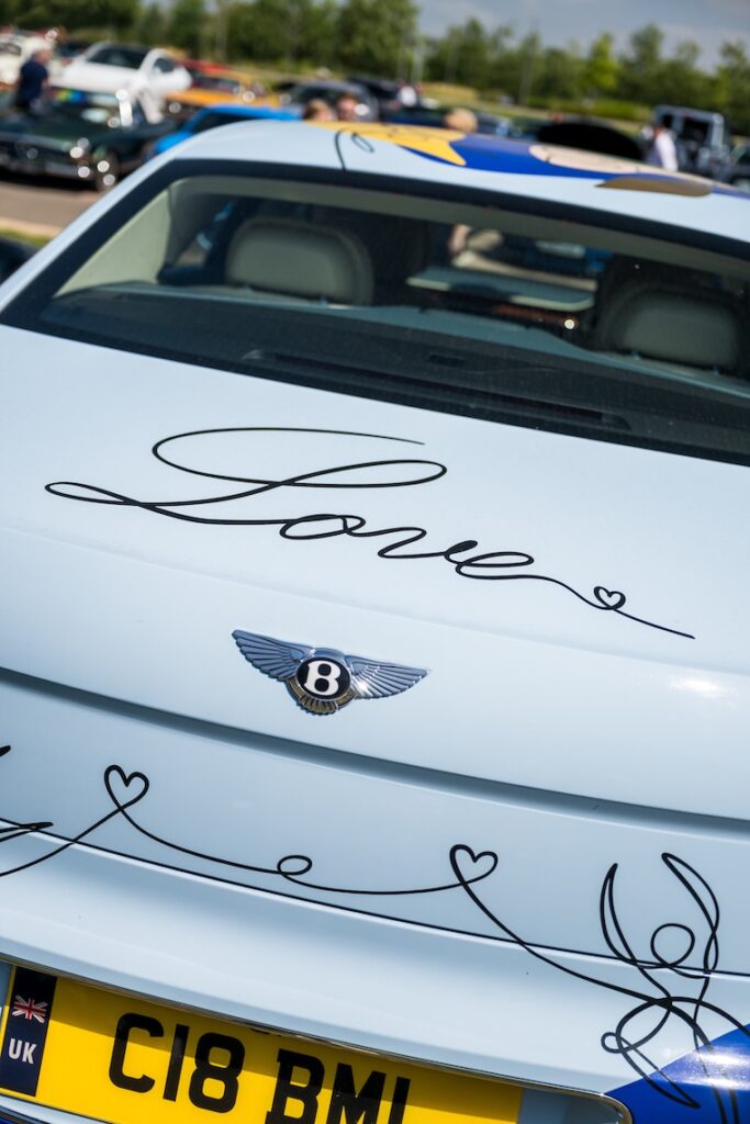 A light blue Bentley with the word 'love' printed on it's boot