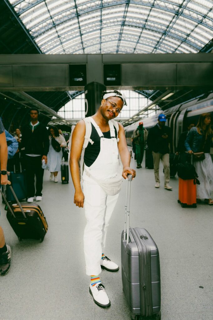 A smiling person in white dungarees smiling on a train platform