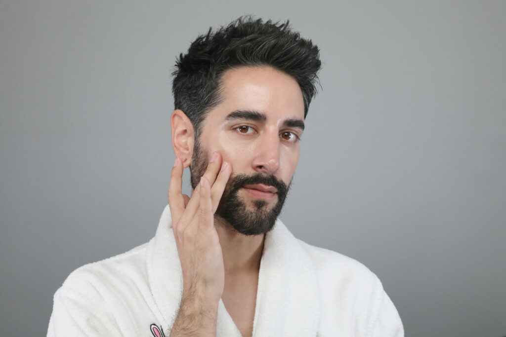 James Welsh in a white dressing gown applying a product to his clean, shining skin