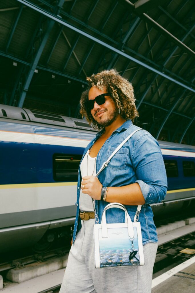 A smiling person wearing a denim jacket standing in front of a Eurostar train