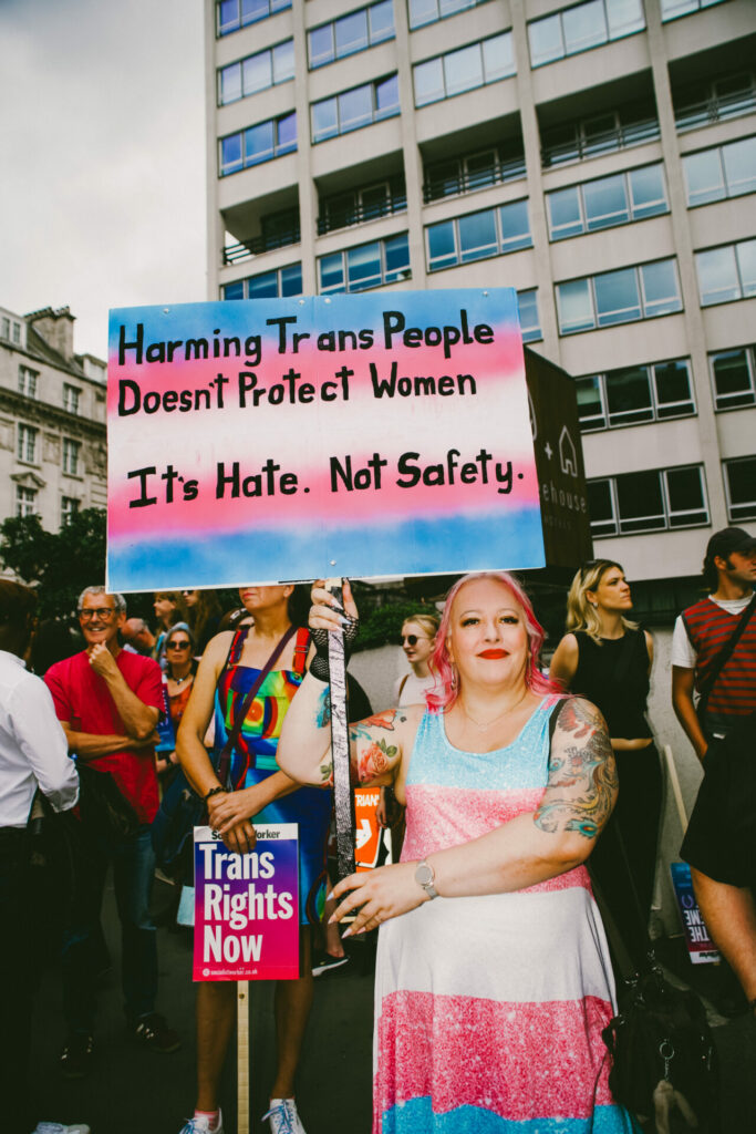 A person holding a “Harming trans women doesn’t protect women” placard
