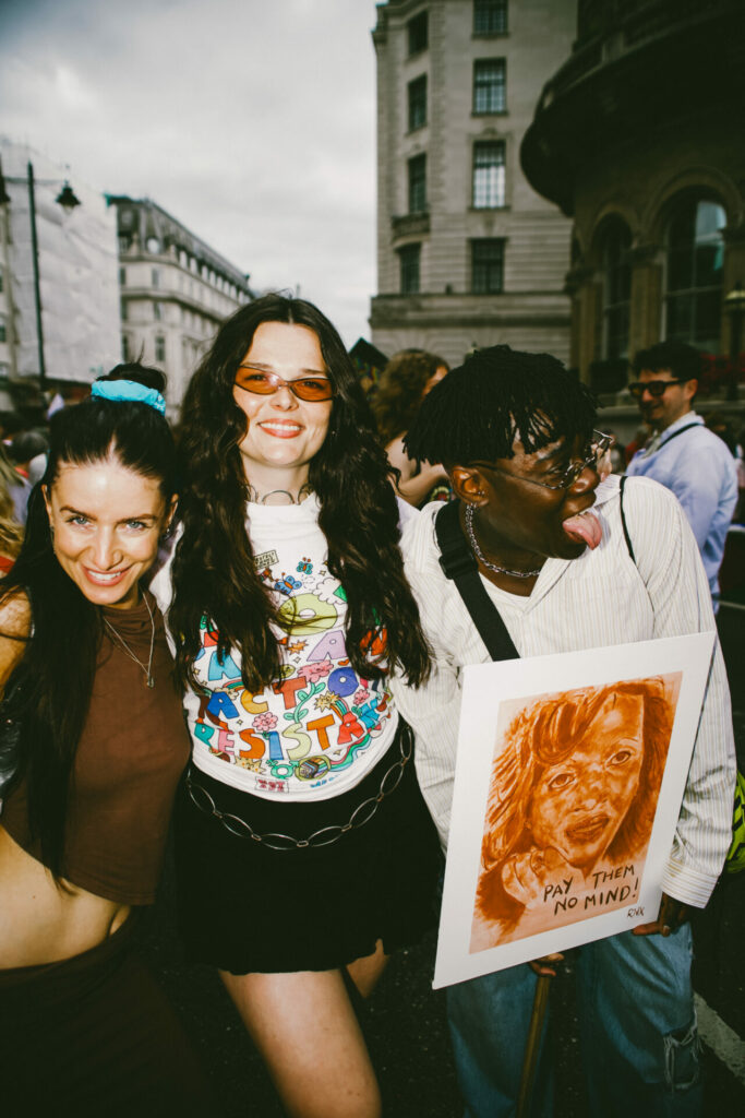 Three diverse people smiling enjoying the trans march