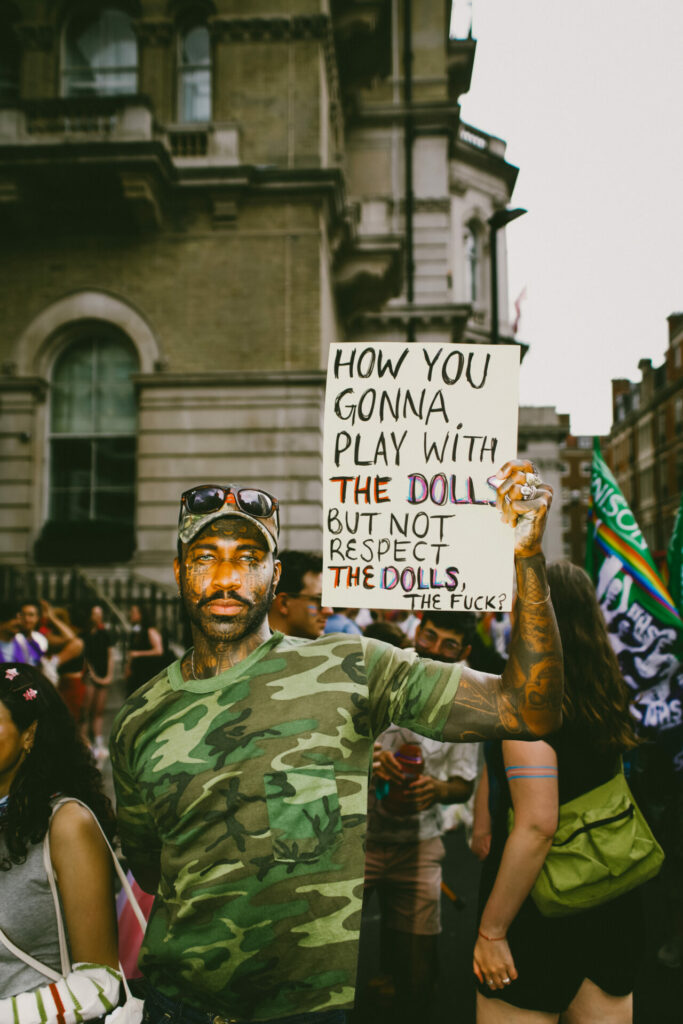 A person holding a placard saying “how you gonna play with the dolls but not protect the dolls”