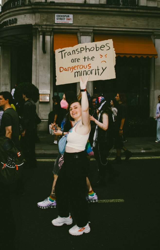 A person carrying a sign saying “transphobes are the minority” on a street in London
