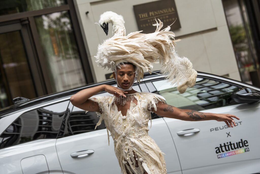 Tyreece Nye in swan-inspired attire posing by a Peugeot