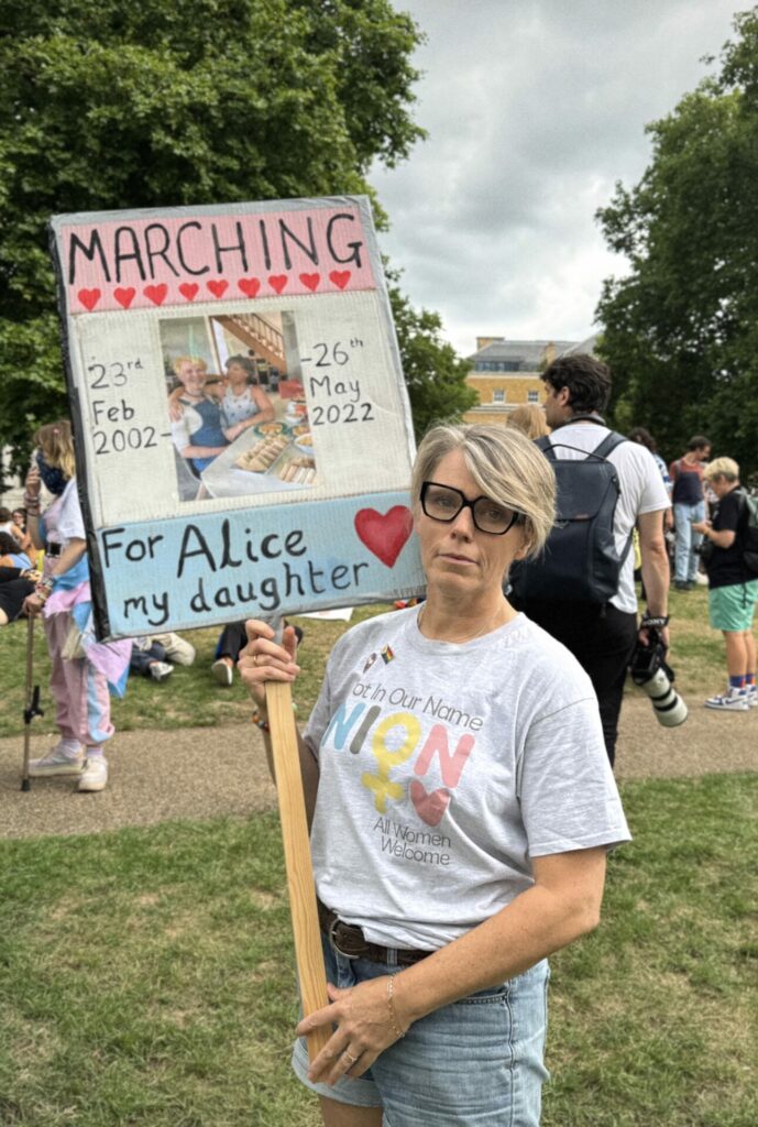 Caroline Litman stands proud with a sign dedicated to her late daughter Alice, displaying a photo of the pair and a heartfelt message