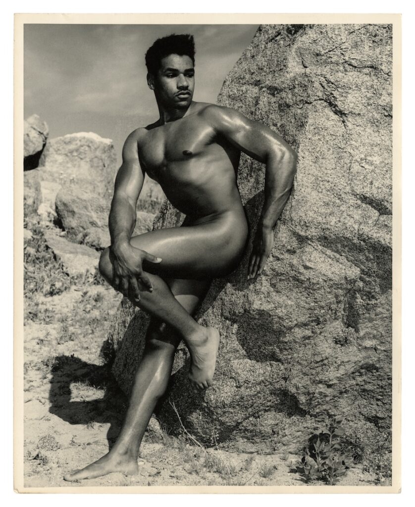 a man naked leaning against a rock