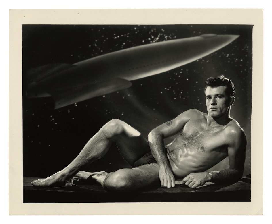 a man lying with a planet in the background, in black underwear