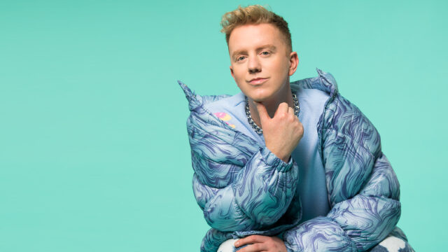 James Barr in blue puffer coat against green background