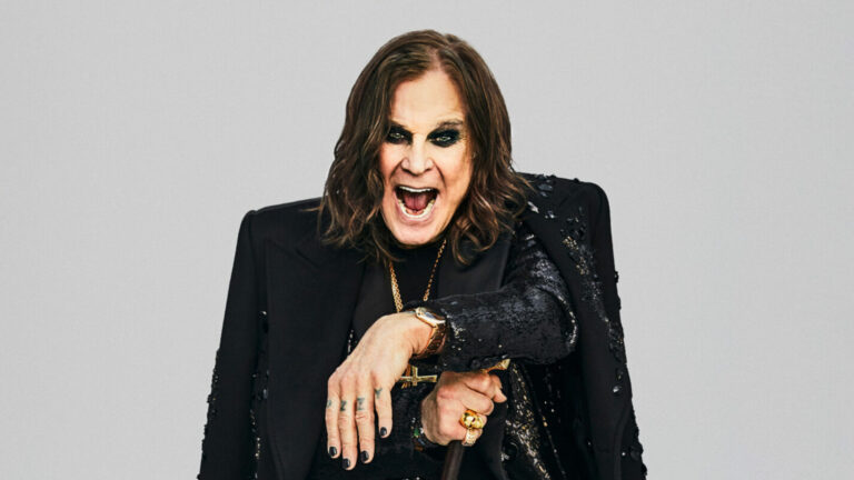 Ozzy wears shirt, trousers, coat and overcoat by Dolce & Gabbana, necklaces by Chrome Hearts, rings by Rockford Collection, bracelets by Luis Morais, watch by Cartier, holding cane by fashionable canes