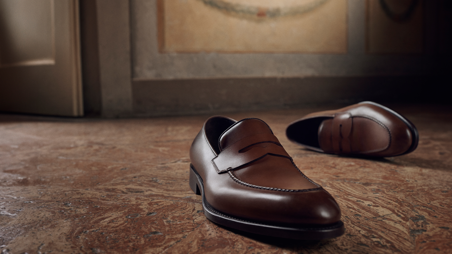 A cloe-up of polished brown leather men's Ferragamo shoes featured in the brand's autumn/winter 2025 campaign.