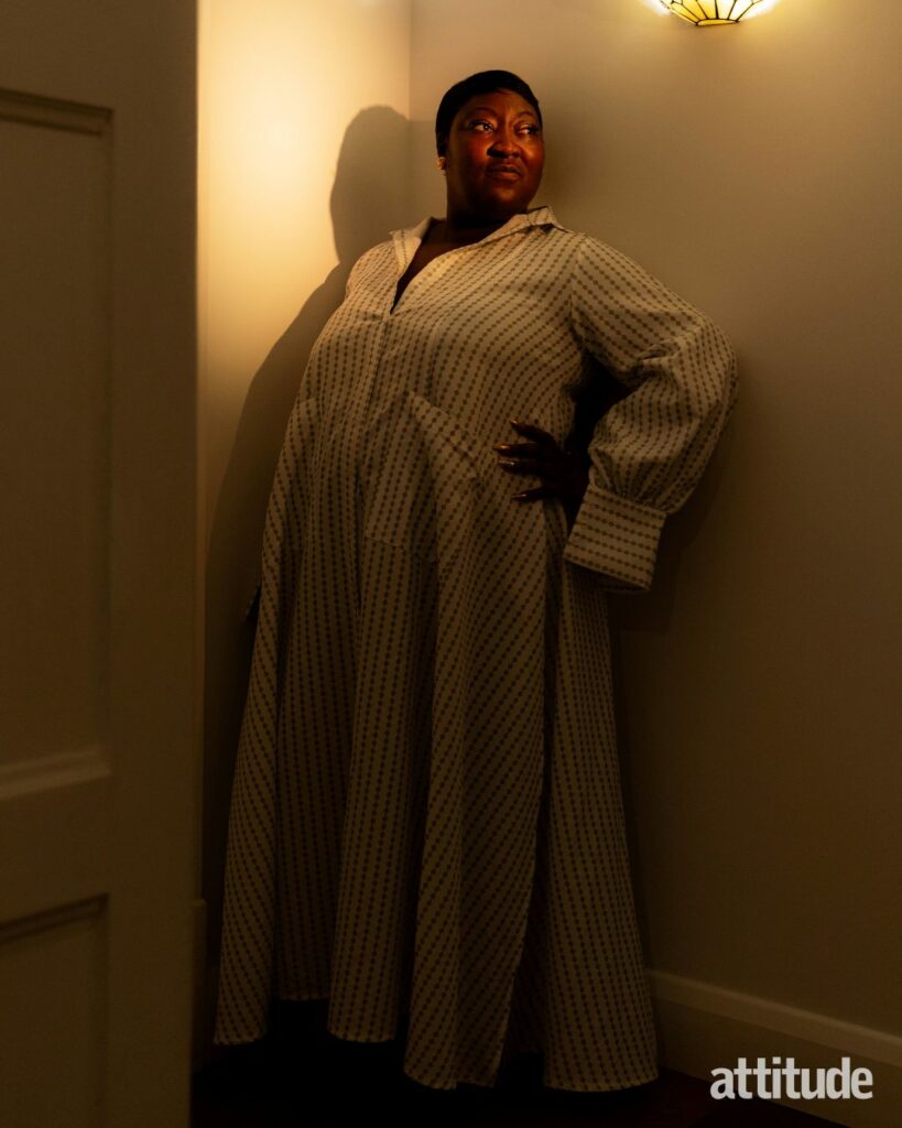 Lady Phyll posing against a wall looking away from the camera