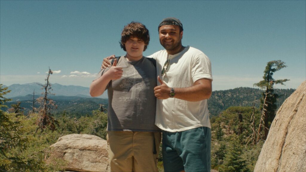 Isaac Krasner and David Johnson III putting a thumbs up whilst cuddling on a cliff