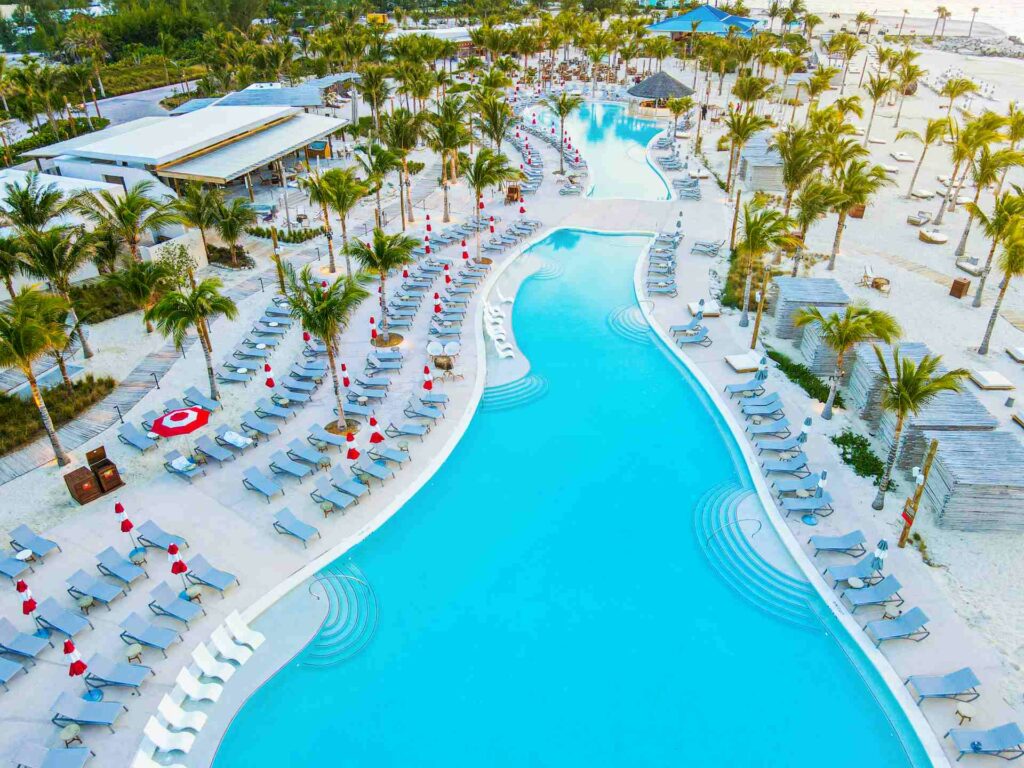Aerial view of a blue pool of water surrounded by sunbeds and palm trees