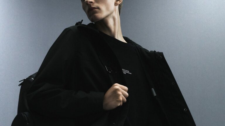 Close-up of a model wearing all black jacket and rucksack from the Dior Men's "Back in Town" capsule collection