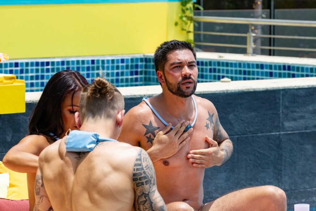 Three people in a pool, one rubbing his chest